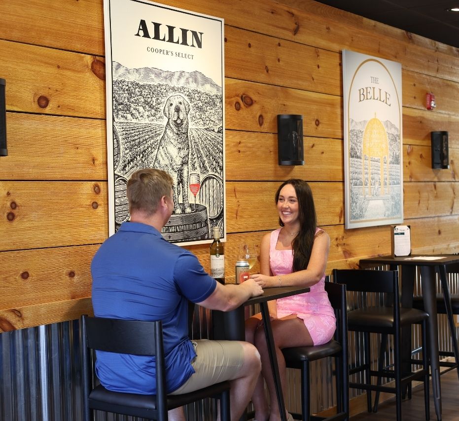a couple sitting at a high top table in the mountain brook emerald isle tasting room